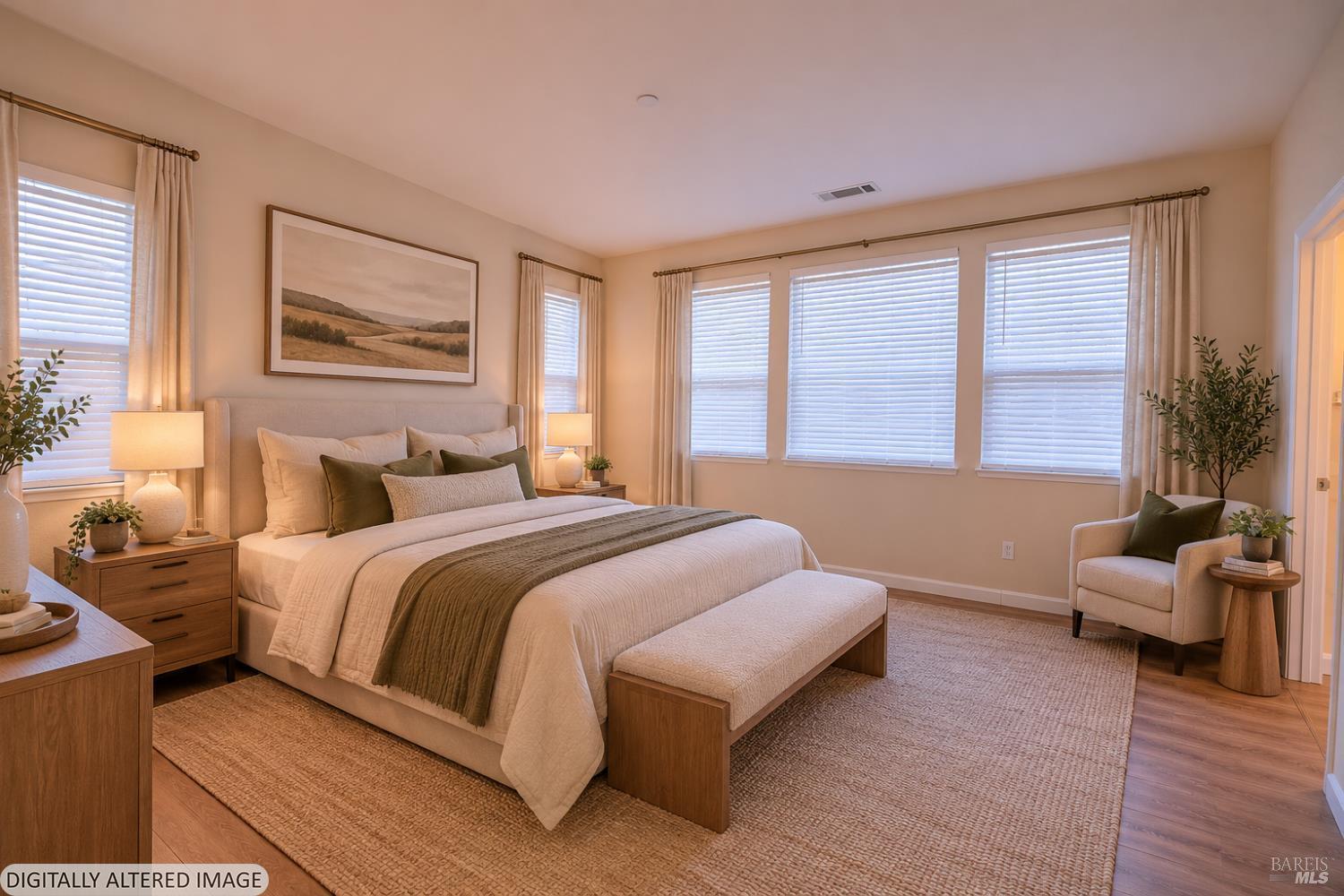 Staged bedroom with a large bed, upholstered bench, and windows with blinds.
