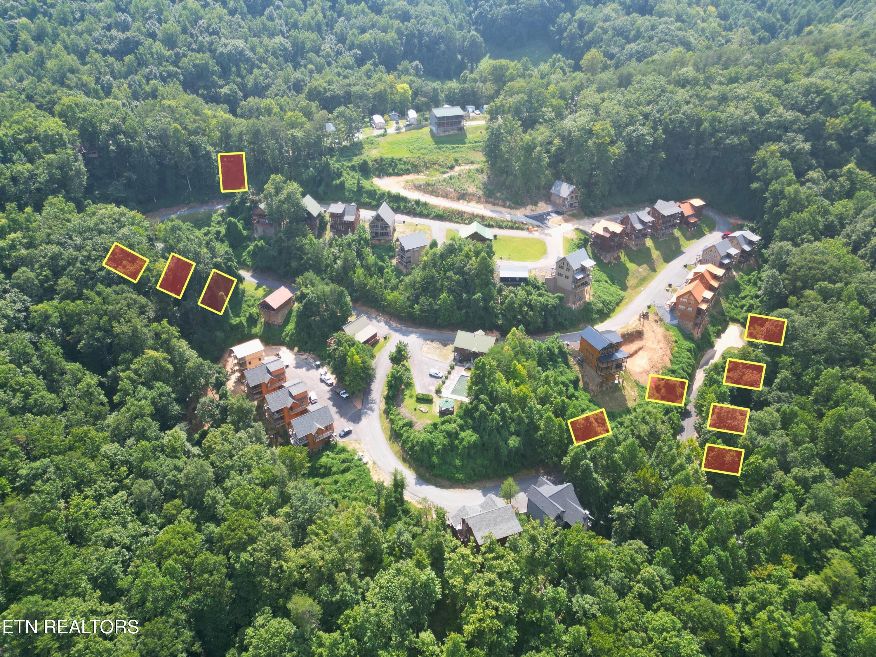 Aerial view of a wooded development with homes and vacant lots outlined in yellow.