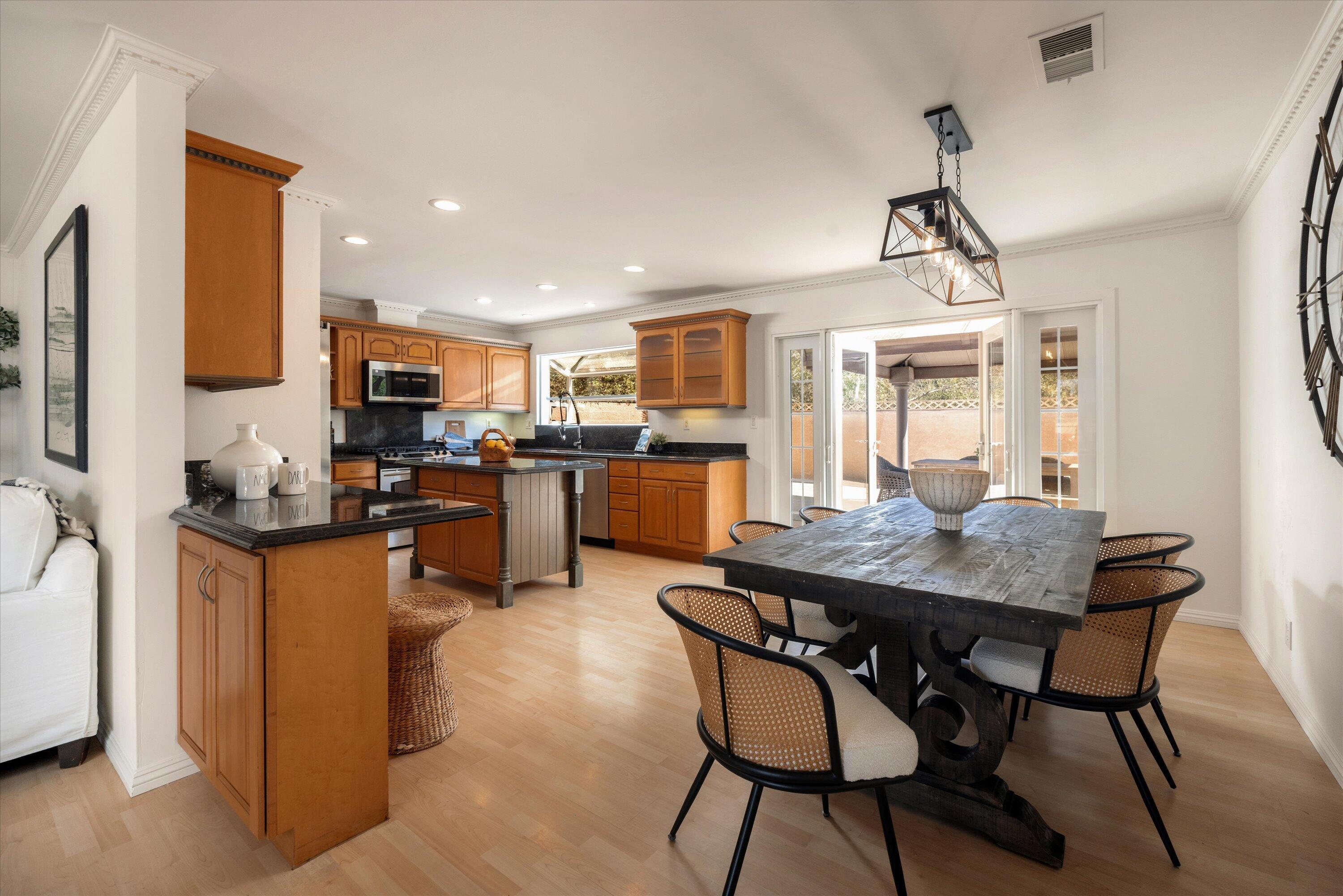 Open kitchen and dining area with warm wood cabinets, a dark dining table, and sliding doors to a patio.