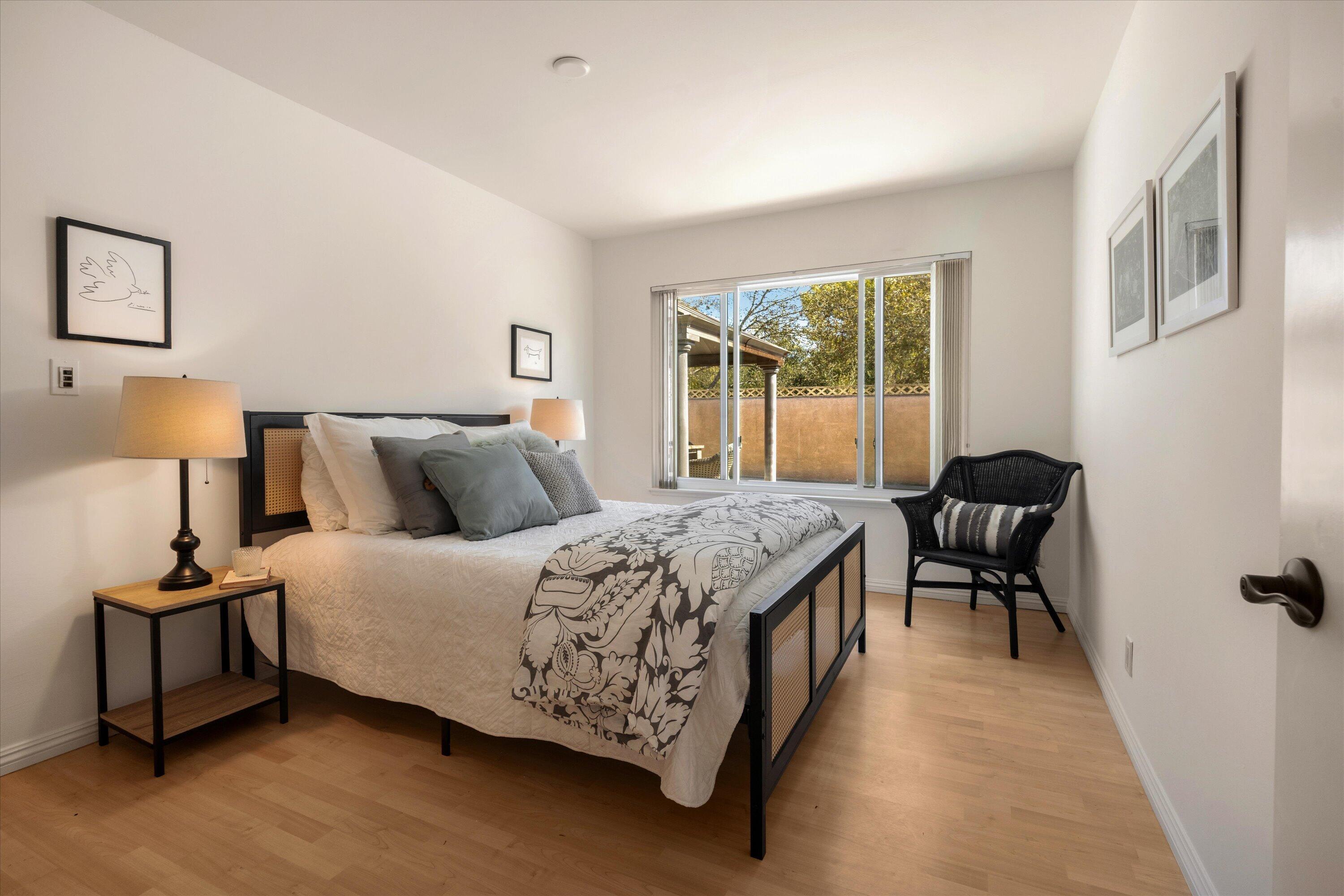 Bedroom with patterned bedding, a black-and-cane bed, and sliding doors to a patio.