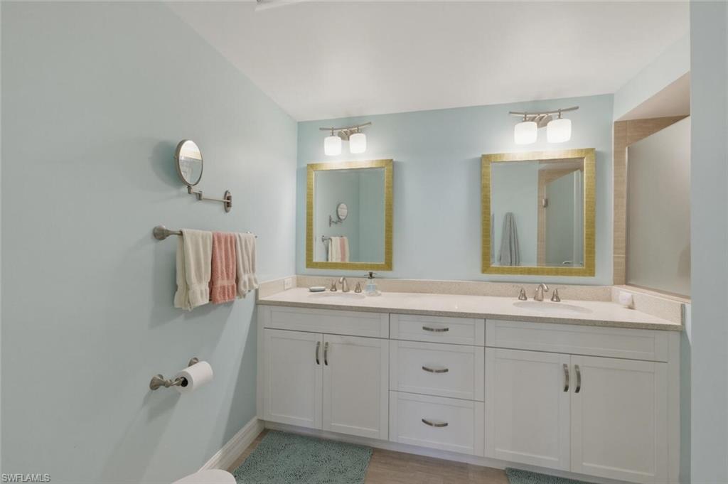 Bathroom with a white double vanity, two gold-framed mirrors, and pale blue walls.