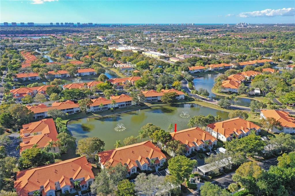Aerial view of orange-roofed residences surrounding a fountain pond, with canals and a distant skyline.