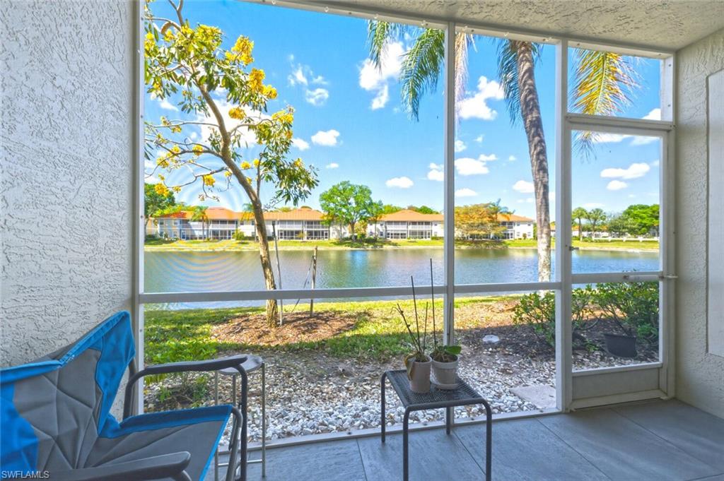 Screened lanai overlooking a lake, furnished with blue chairs and a small table.