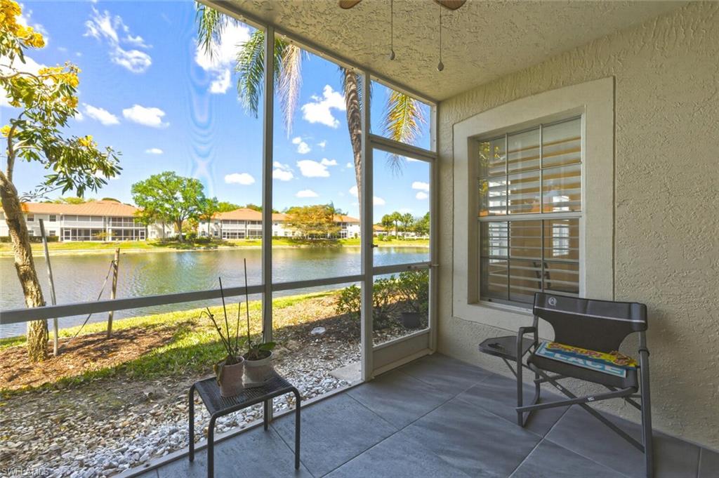 Screened lanai with two chairs overlooking a lake and homes across the water.
