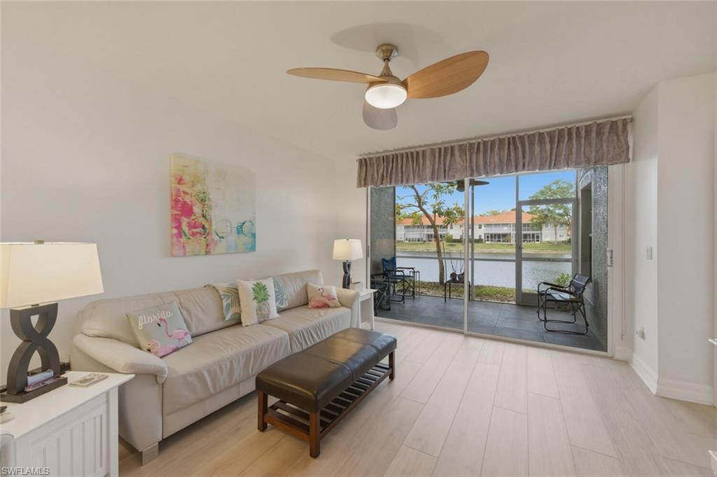 Living room with a cream sofa and sliding doors overlooking a canal from the screened lanai.