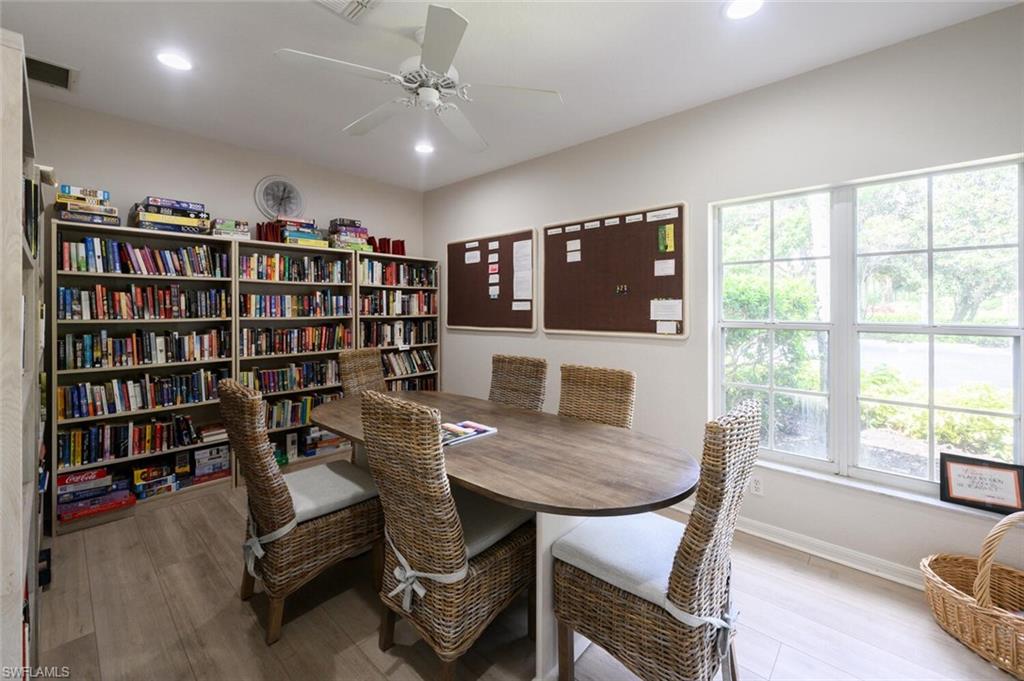 Community library with book-filled shelves, a conference table, wicker chairs, and bright windows.