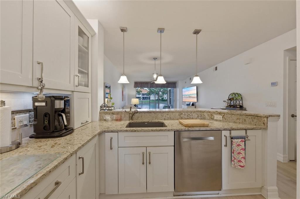 Kitchen with white cabinetry, granite counters, stainless-steel dishwasher, and water visible beyond the living area.