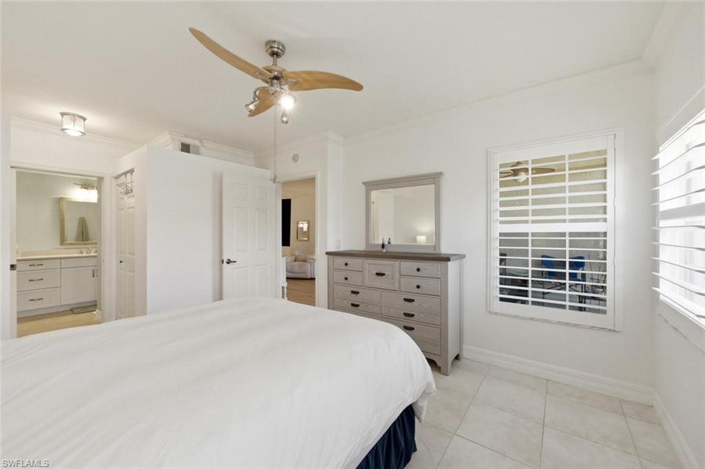 Bedroom with a white bed, ceiling fan, gray dresser, and adjoining bathroom.