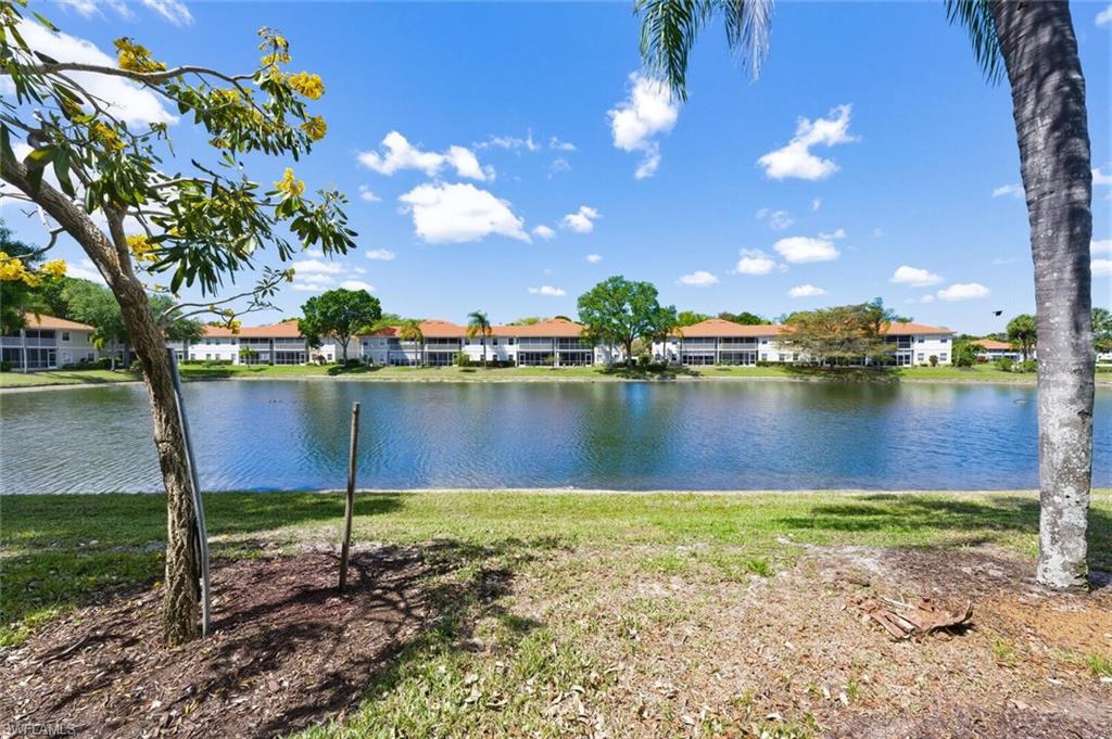 Lakefront view across the water to low-rise homes with screened lanais and terracotta-colored roofs.