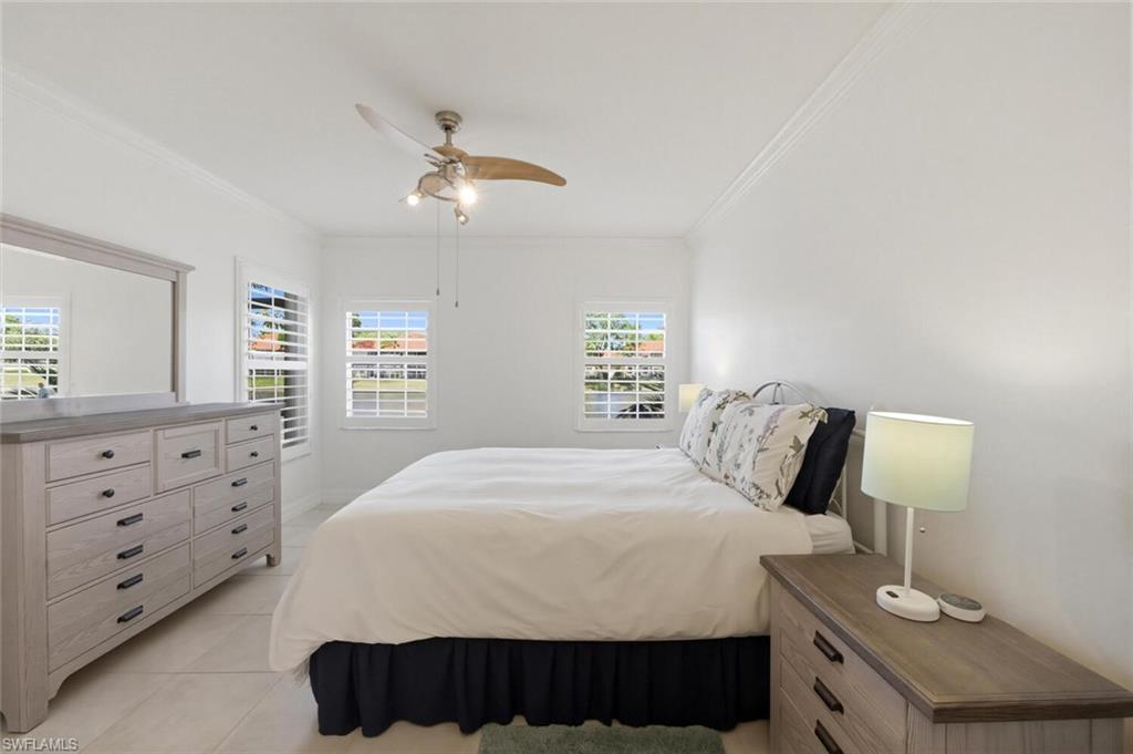 Furnished bedroom with a white bed, shuttered windows, and matching wood-tone dressers.