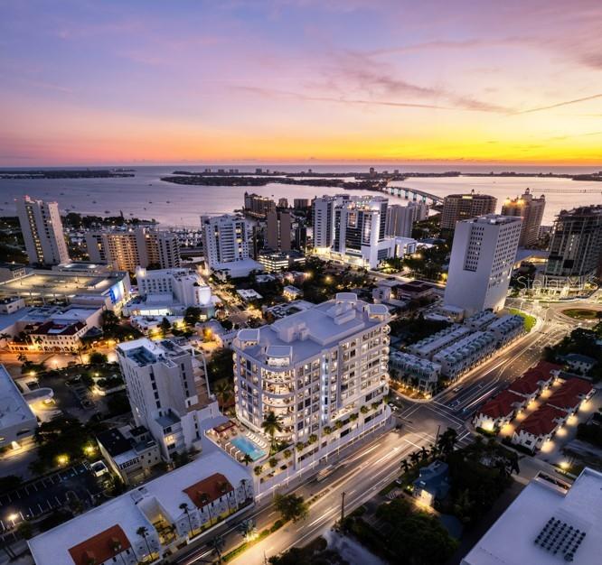 Aerial view of Sarasota’s waterfront skyline, bay, and bridge at sunset.