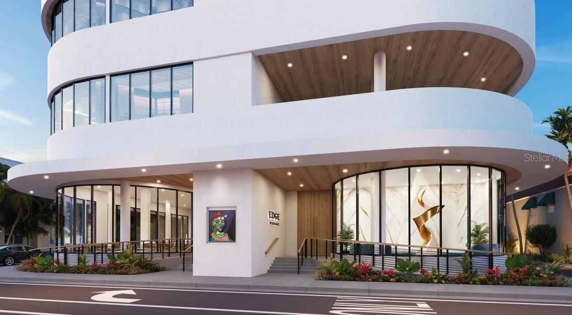 Curved white condominium entrance with floor-to-ceiling windows, wood soffits, and landscaped frontage.