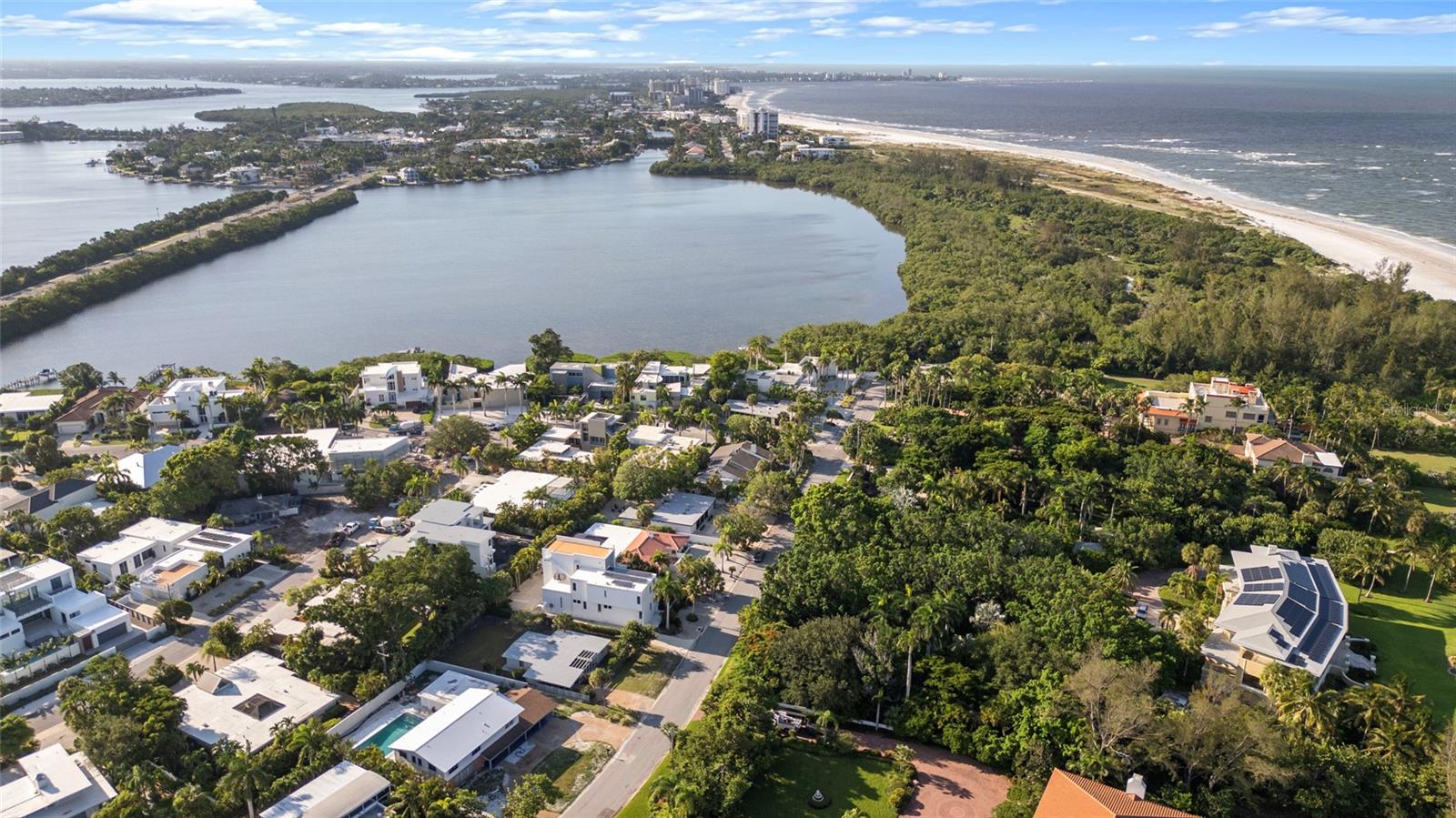 Aerial view of a waterfront neighborhood between a broad bay and a long sandy beach.