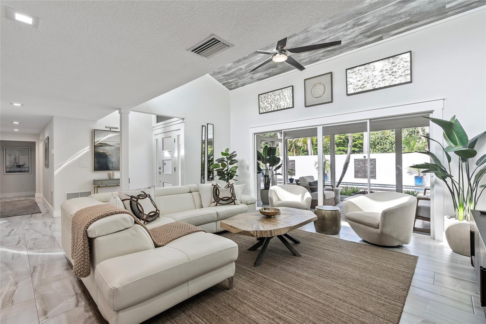 Living room with a white sectional, sculptural coffee table, and sliding doors to the pool patio.