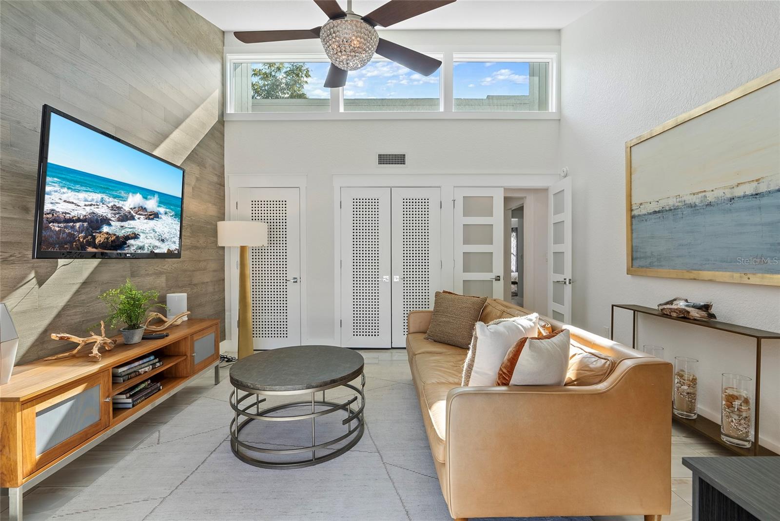 Living room with a tan leather sofa, round coffee table, and high clerestory windows.