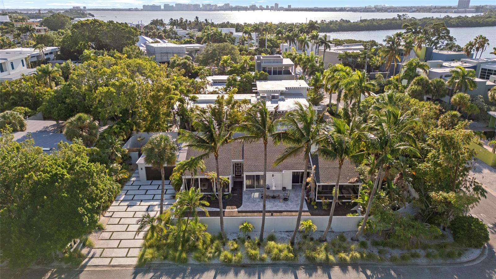 Aerial view of a modern home framed by palms, with waterways and Sarasota’s skyline beyond.