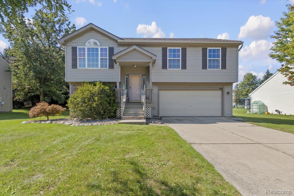 Split-level house with a covered entry, attached garage, and broad front lawn.