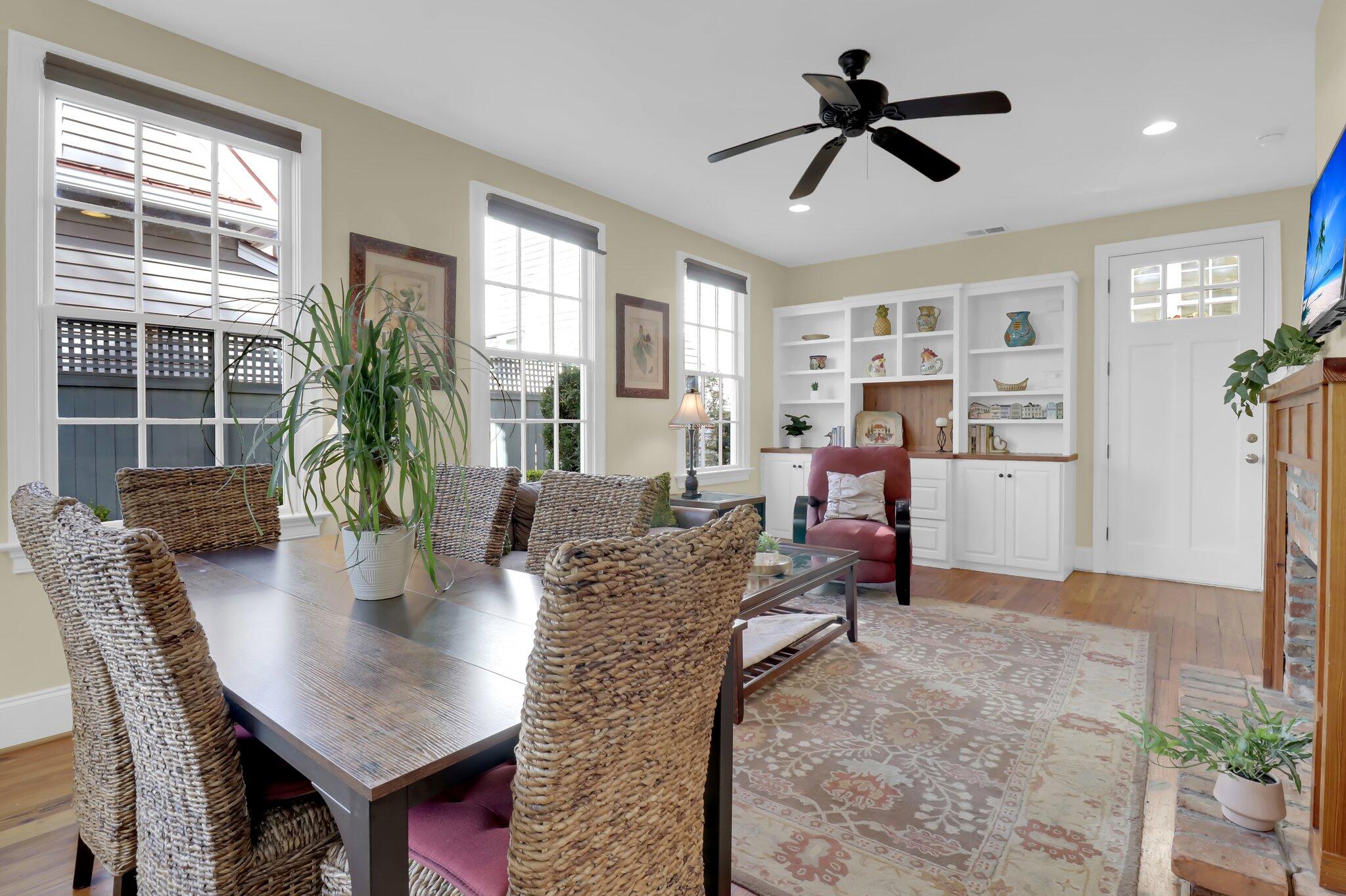 Living and dining room with woven chairs, white built-ins, and large windows.