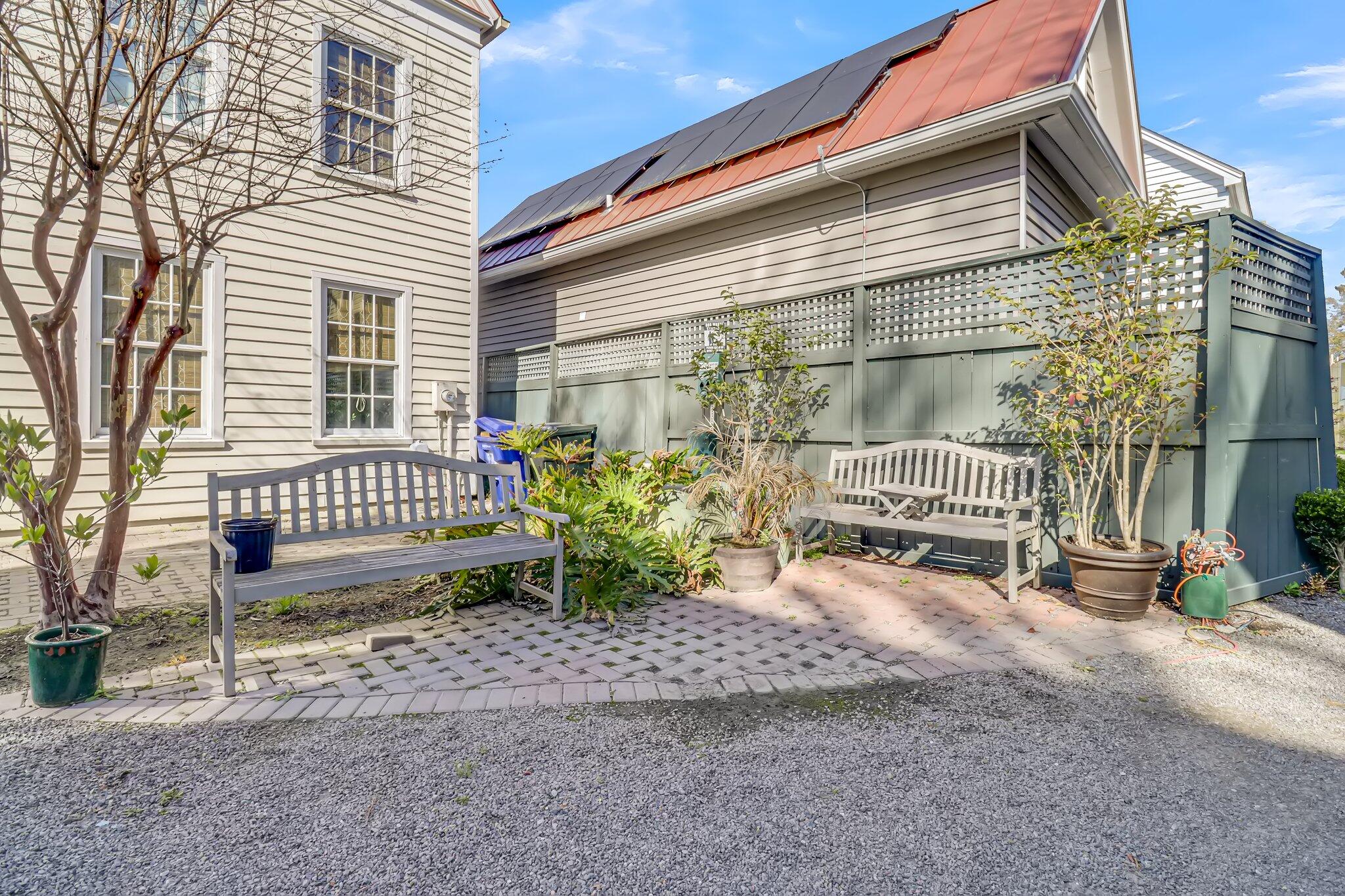 Outdoor courtyard with benches, potted plants, a privacy fence, and rooftop solar panels.