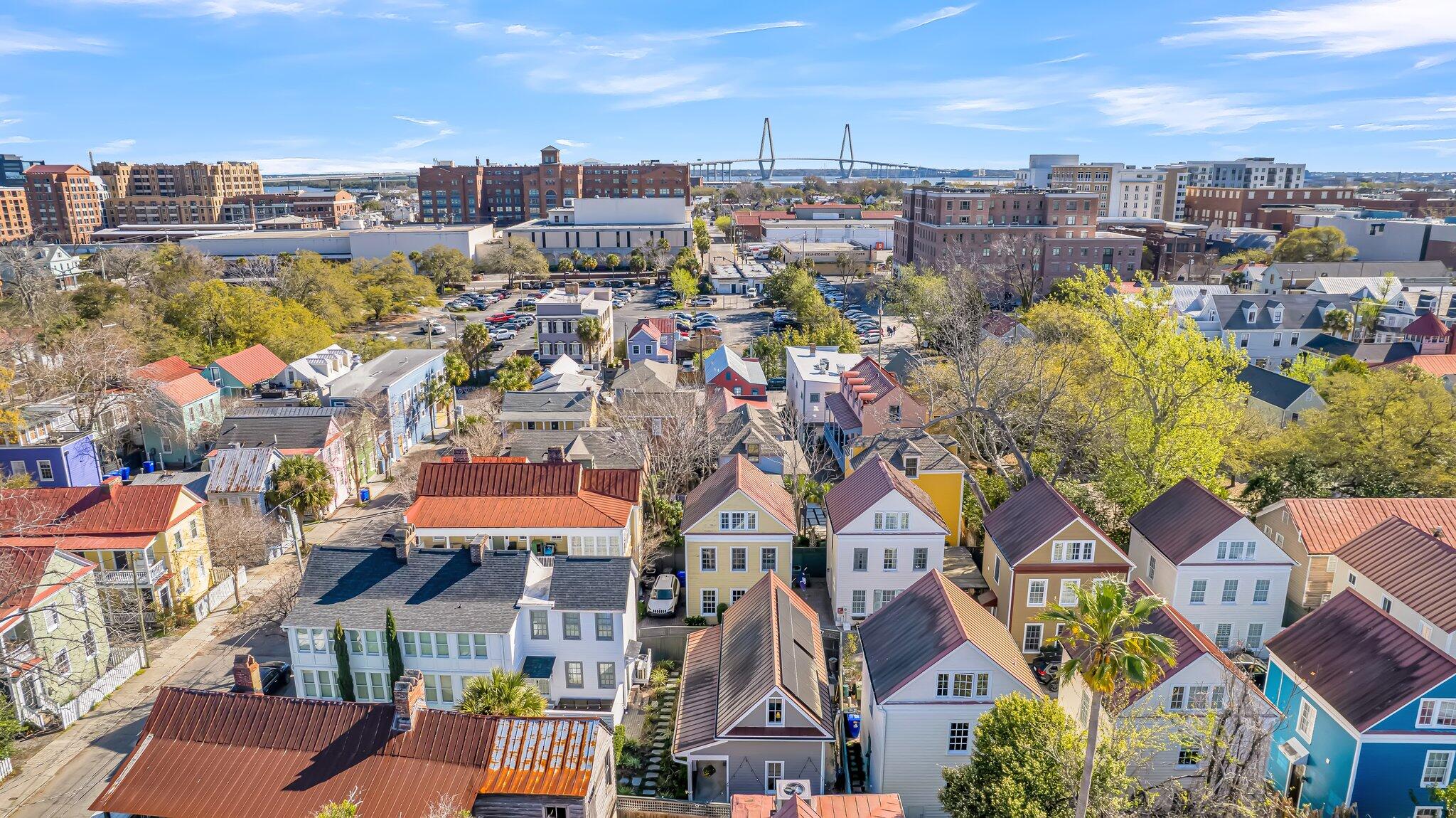 Aerial view of Charleston homes with downtown buildings and the Ravenel Bridge in the distance.