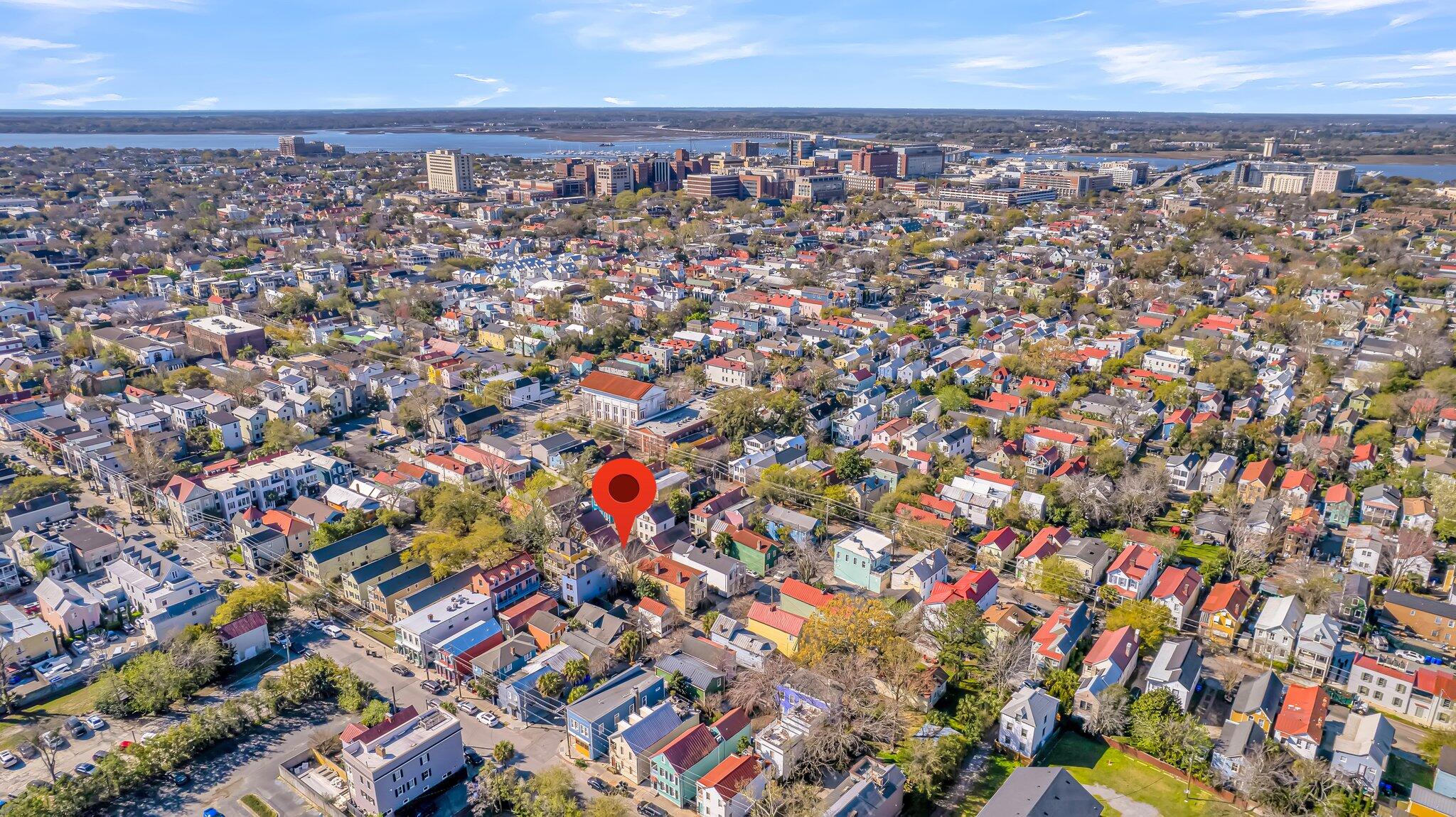 Aerial view of a neighborhood marked by a red pin, with downtown buildings and water in the distance.