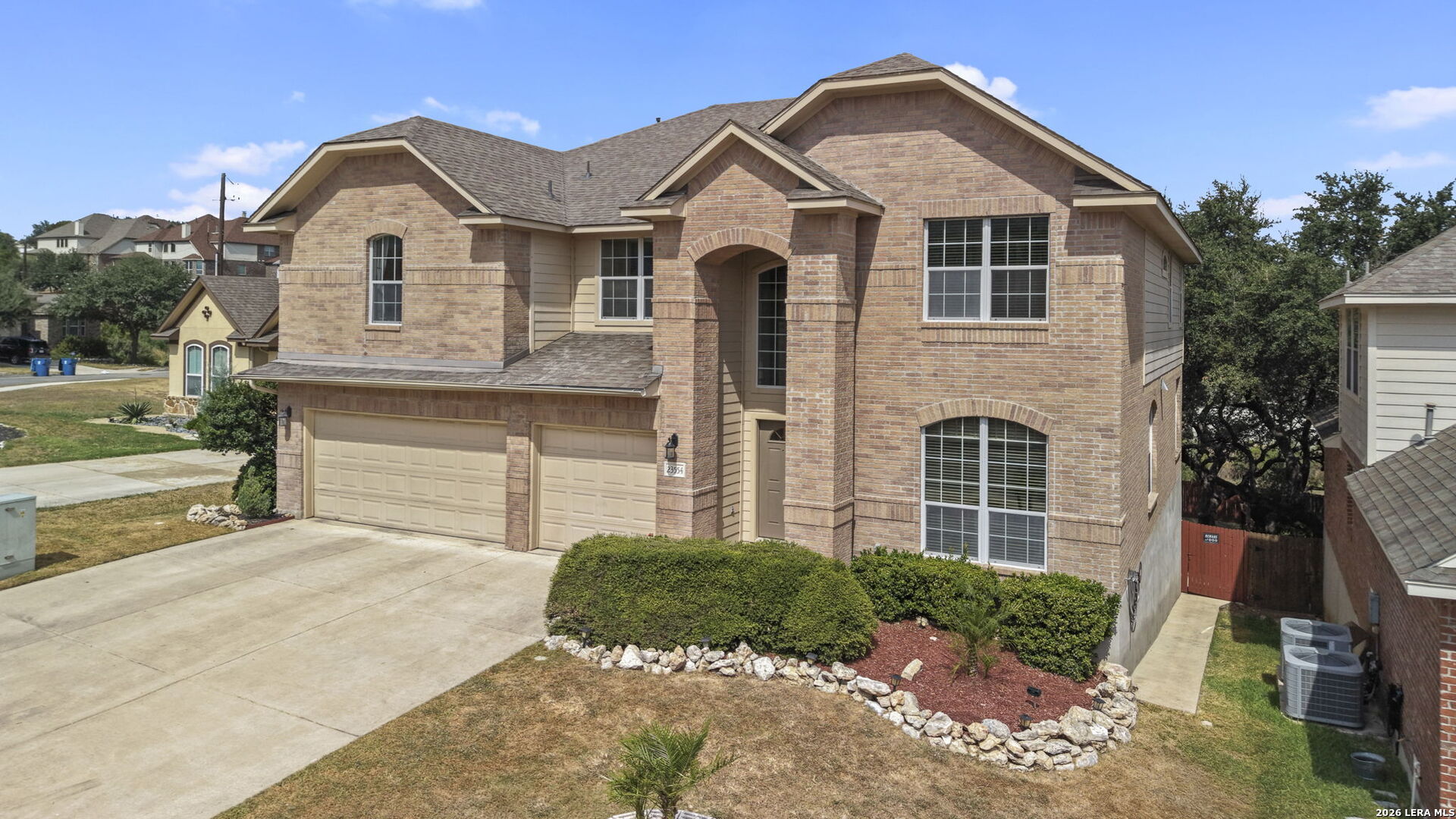 Two-story brick house with a double garage, arched entry, and landscaped front yard.