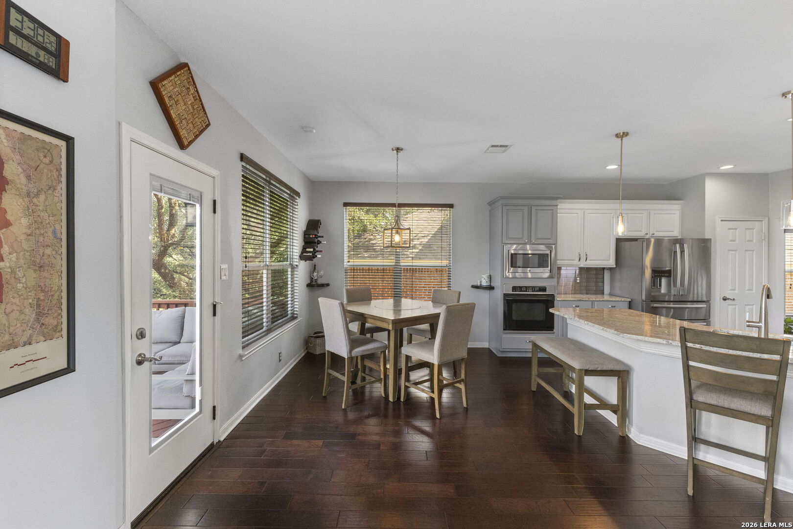 Kitchen and dining area with a large island, stainless steel appliances, and dark wood floors.