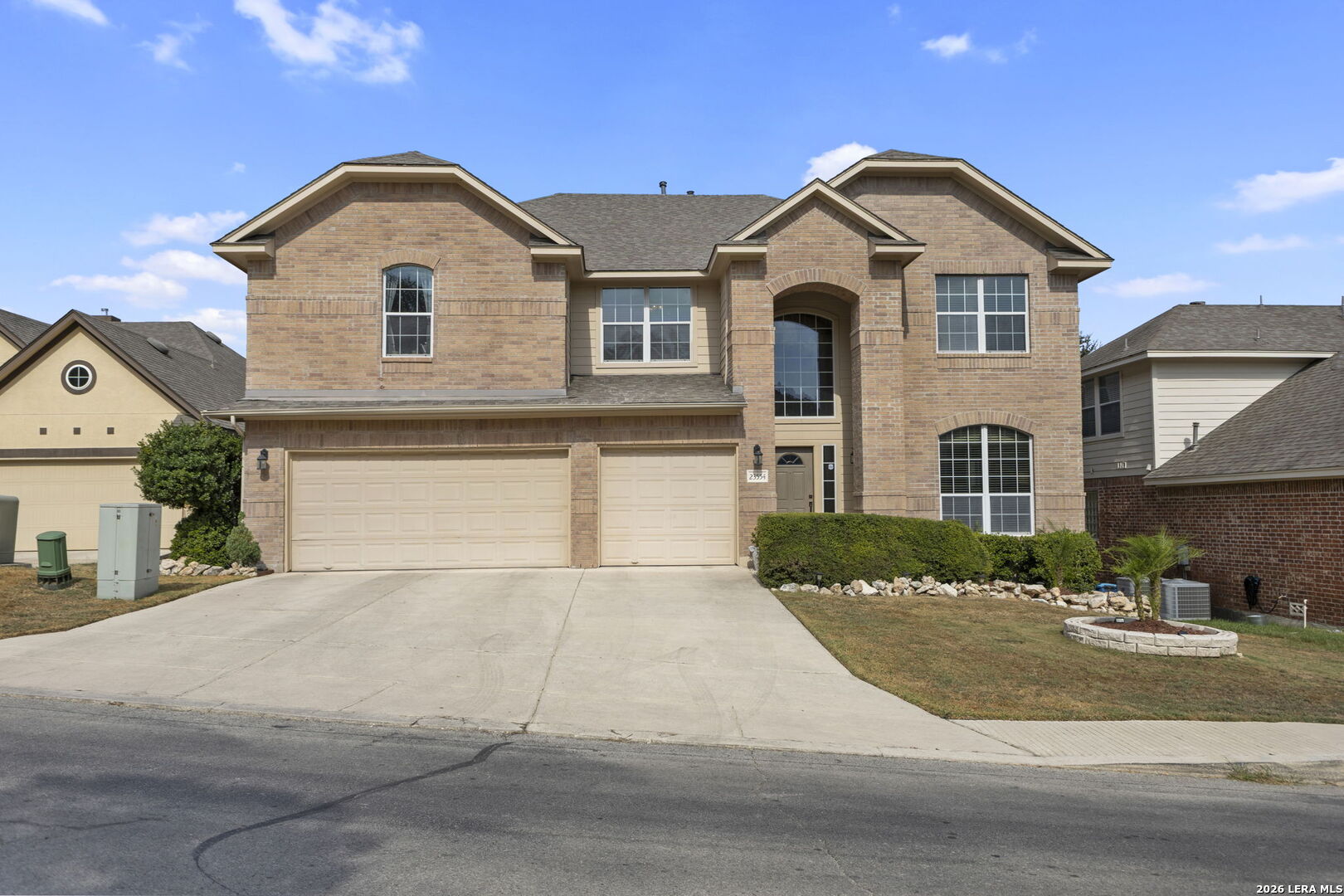 Two-story brick home with a three-car garage, arched entry, and wide driveway.