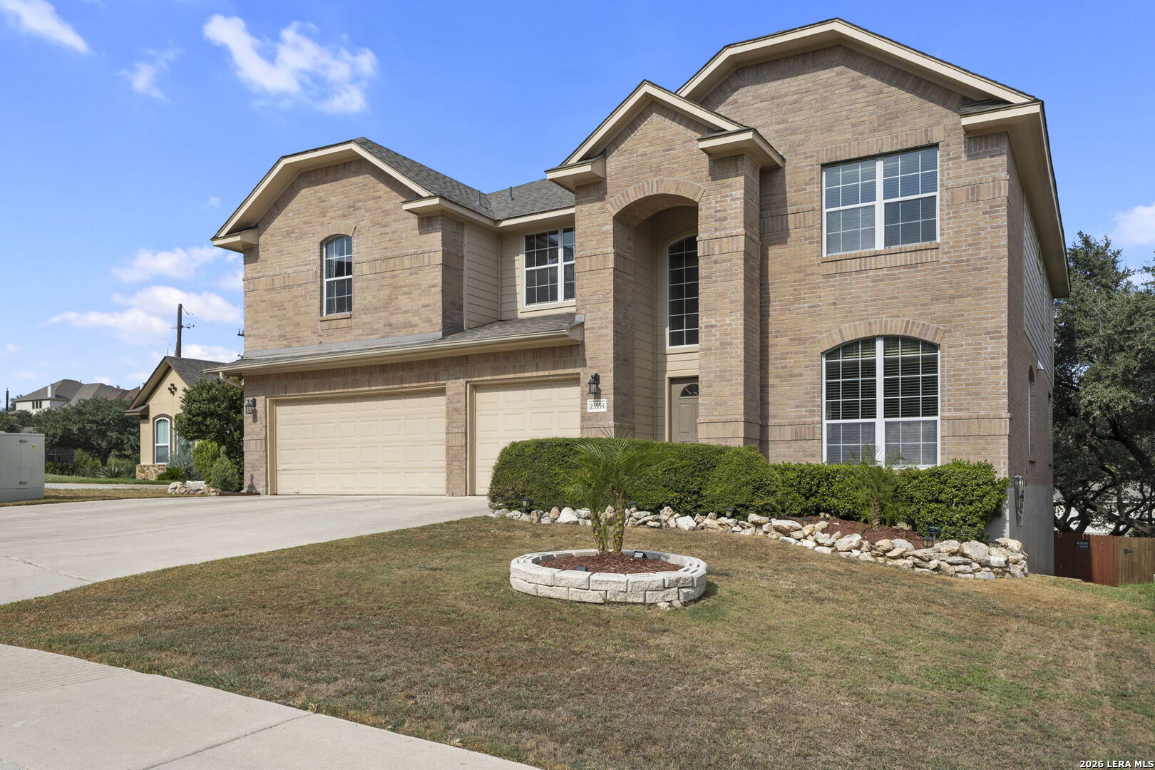 Two-story brick house with a covered entry, double garage, and landscaped front yard.