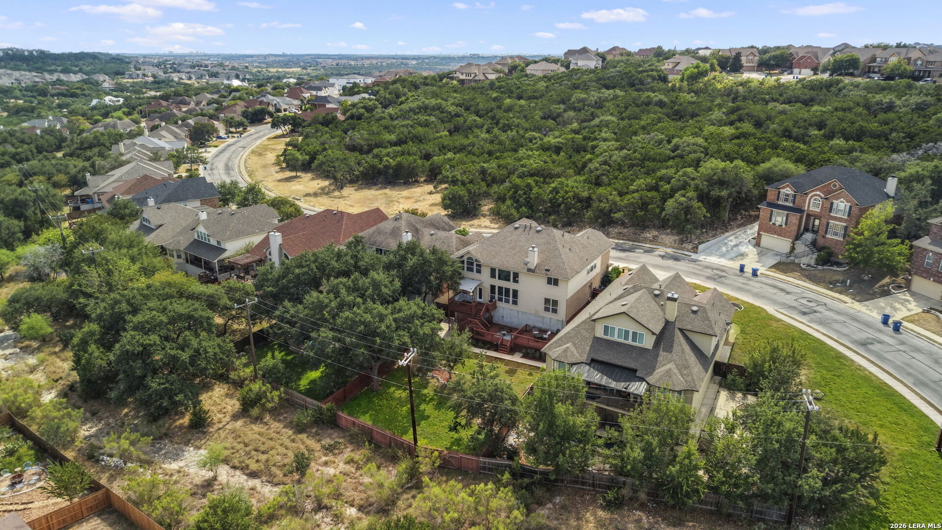 Aerial view of neighborhood homes bordering a wooded greenbelt.