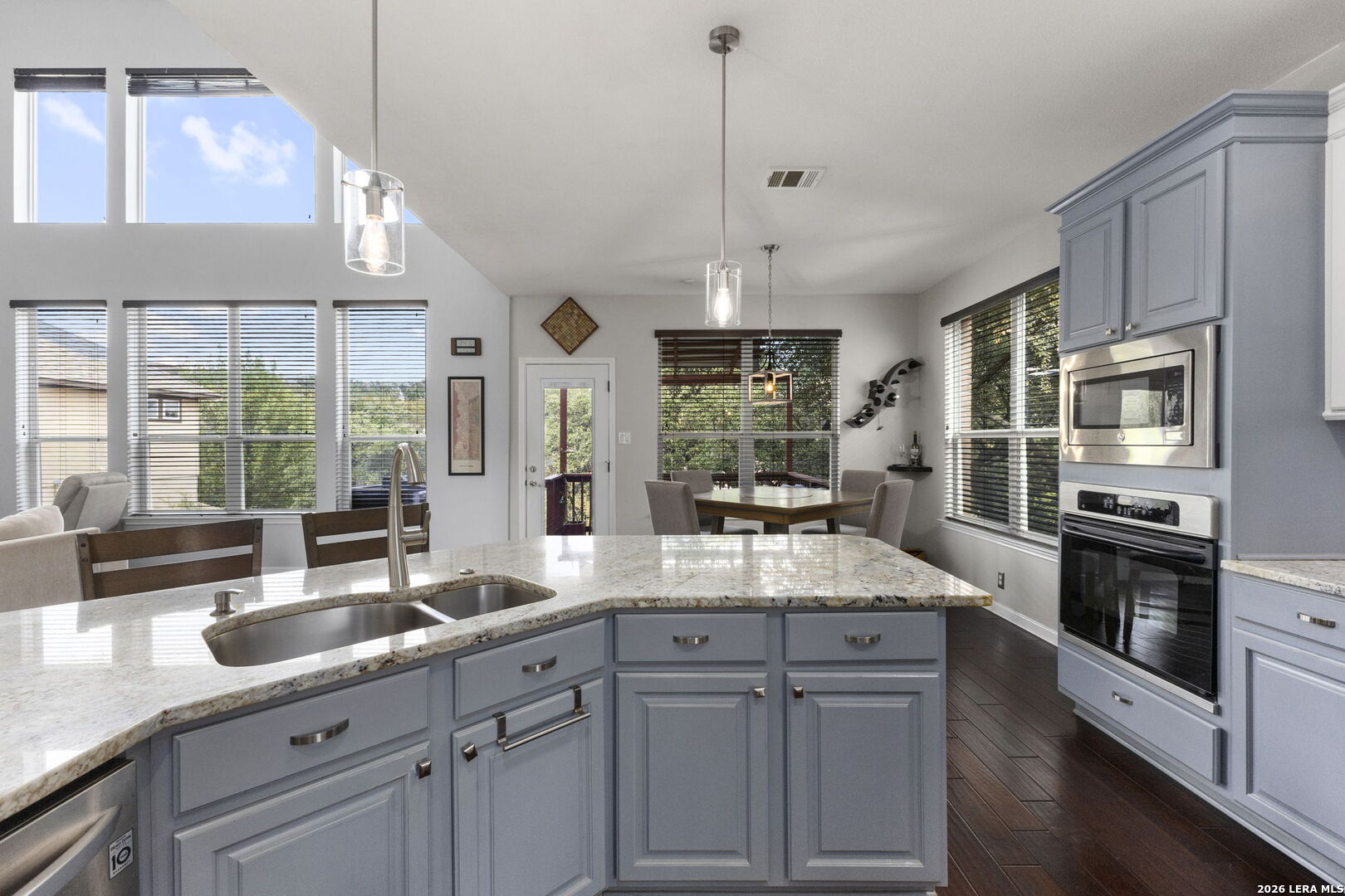 Kitchen with blue cabinetry, a granite island, stainless steel appliances, and an adjoining dining area.