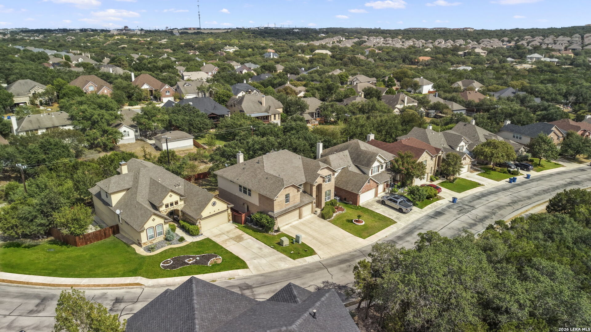 Aerial view of a residential neighborhood with detached homes, tree-lined yards, and streets.
