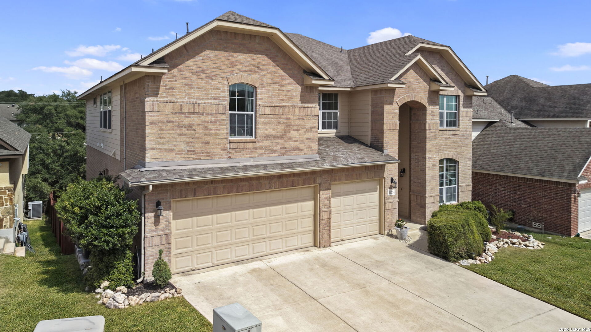 Two-story brick house with a tan double garage and arched front entry.