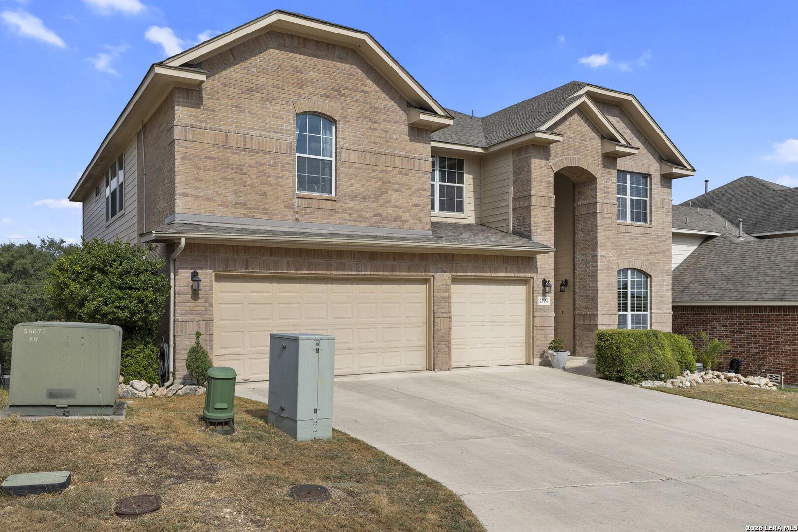 Two-story brick house with a double garage, arched entry, and broad driveway.