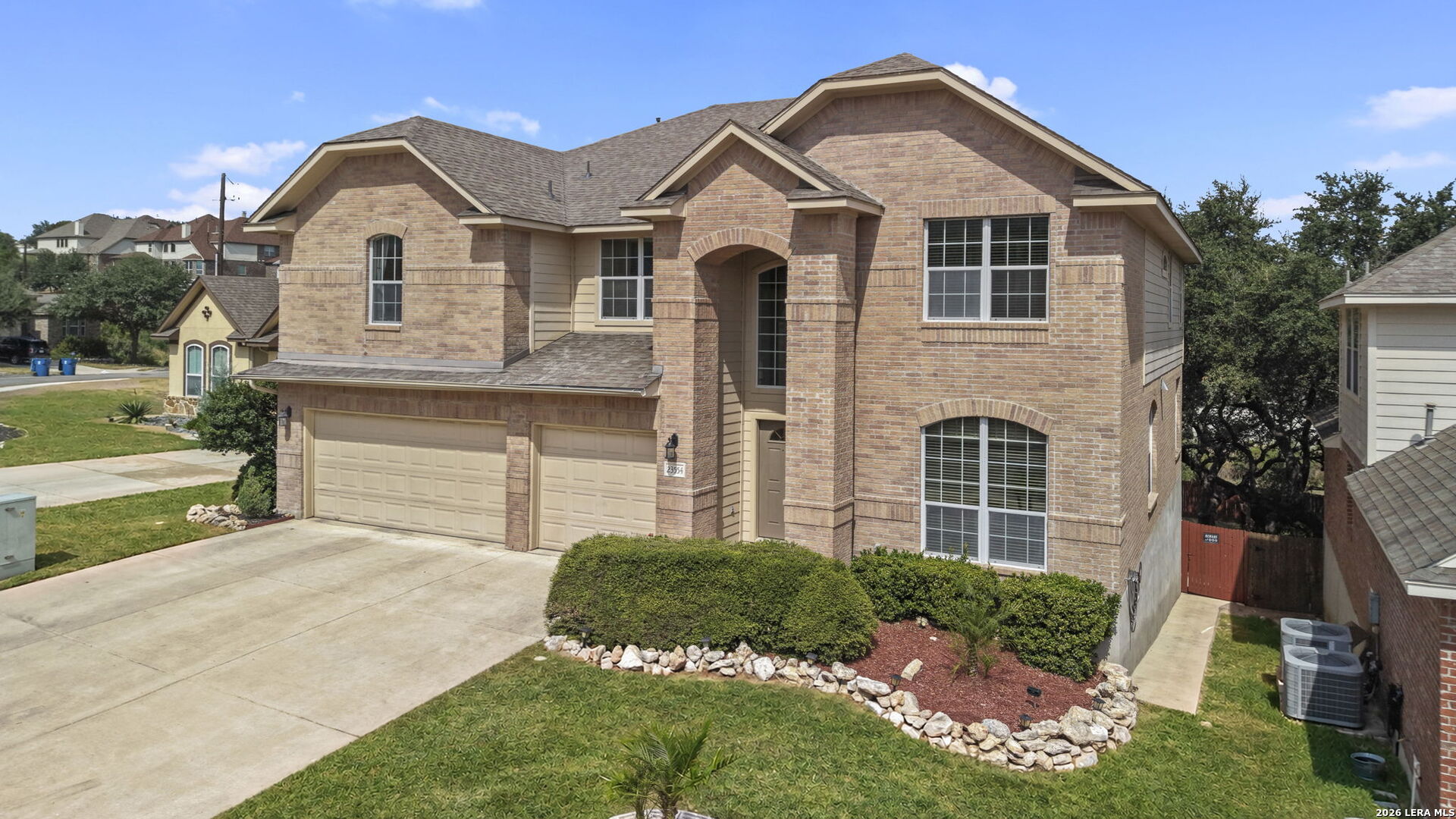 Two-story brick house with a double garage, arched entry, and landscaped front yard.