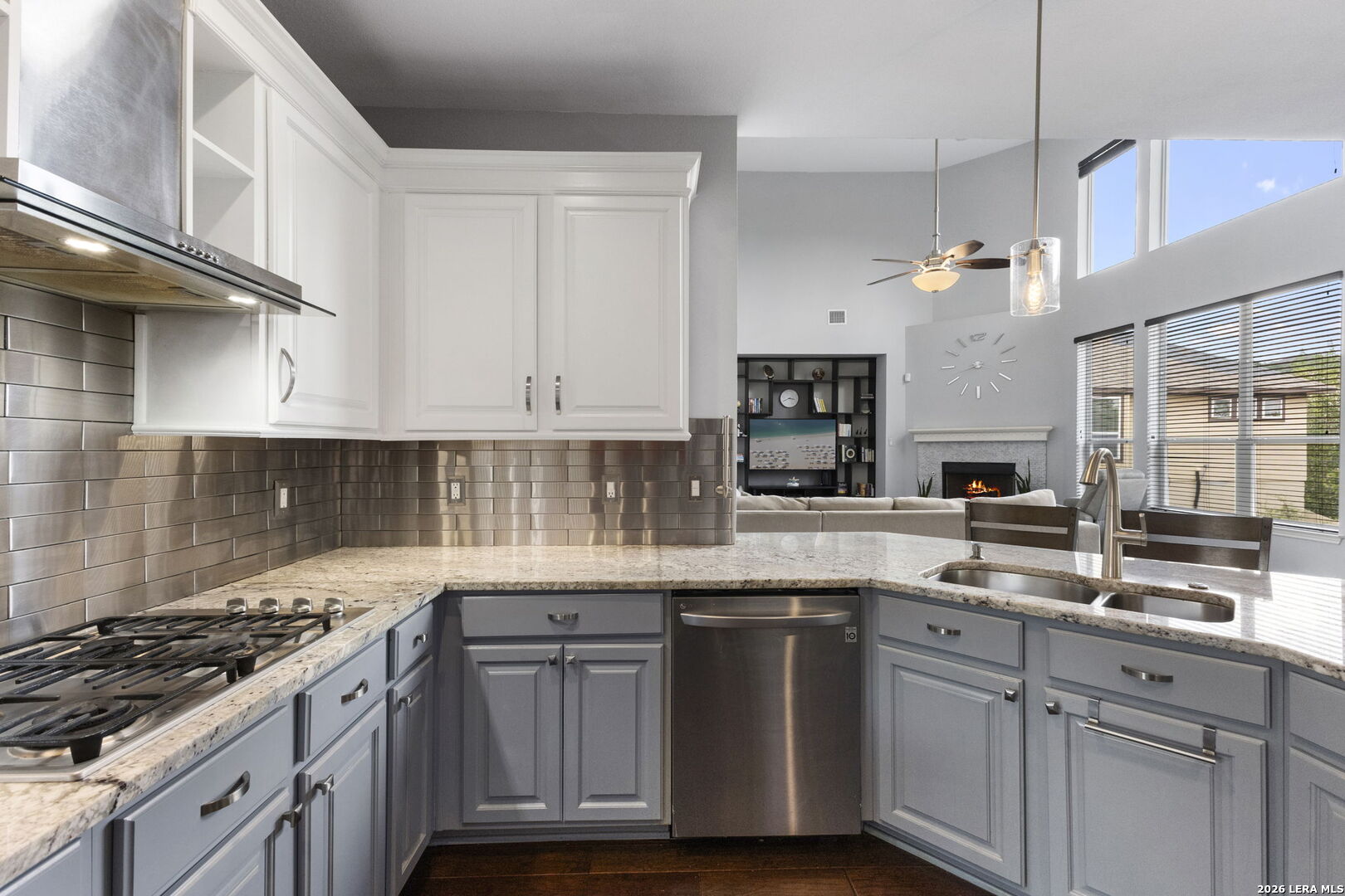 Kitchen with blue-gray cabinets, granite counters, stainless appliances, and an open view of the living room.