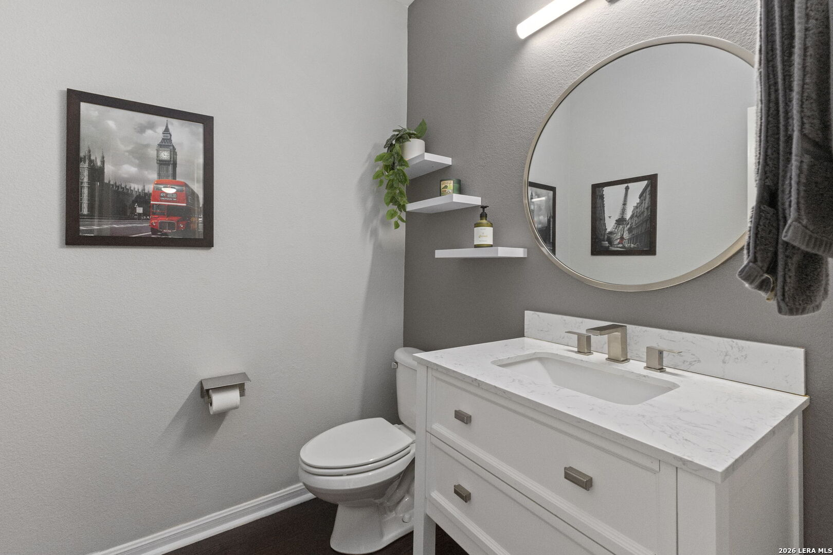 Bathroom with a white vanity and marble-pattern counter beneath a round mirror.