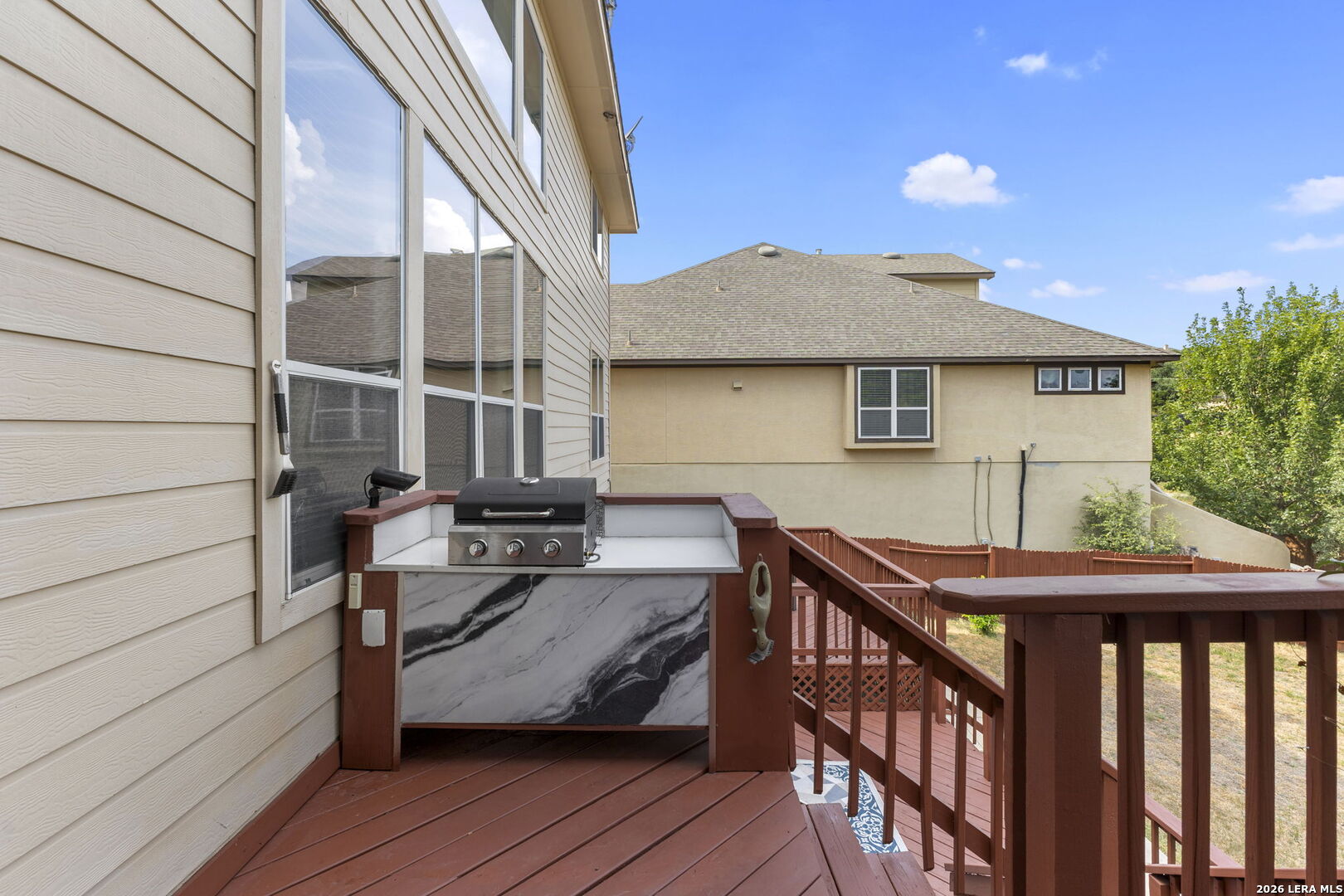 Raised wood deck with a built-in grill, counter, and stairs.
