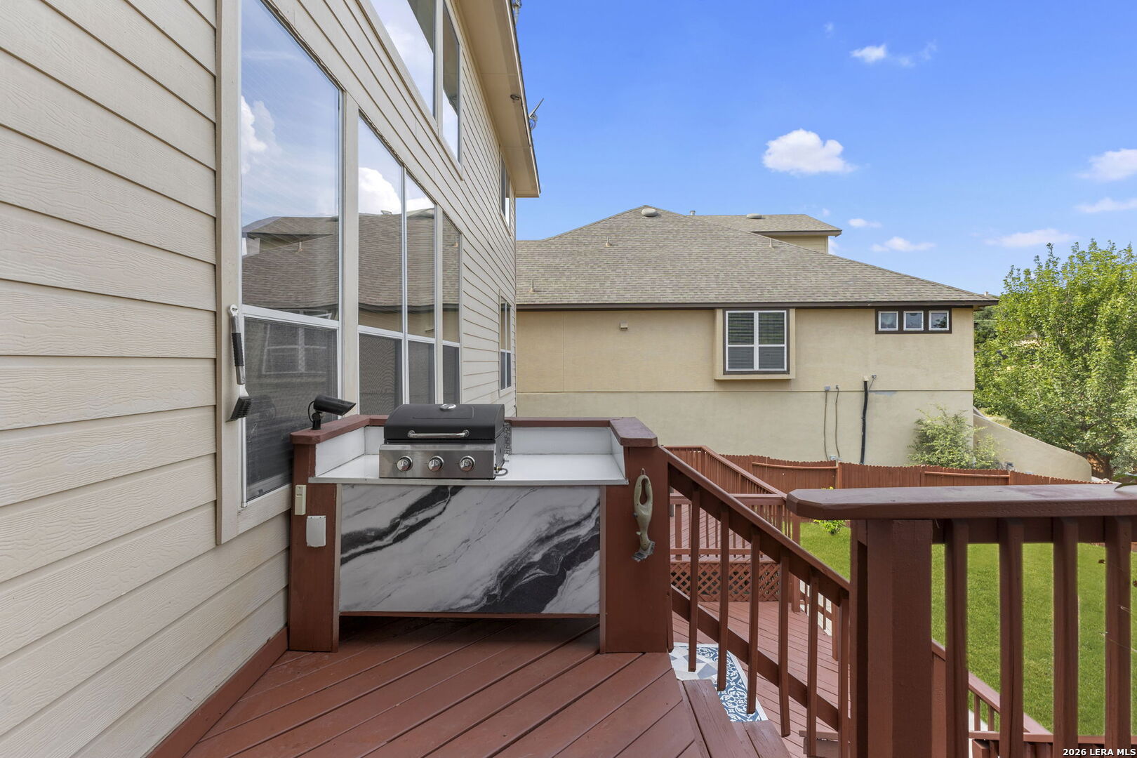 Wood deck with a built-in gas grill and counter overlooking the backyard.