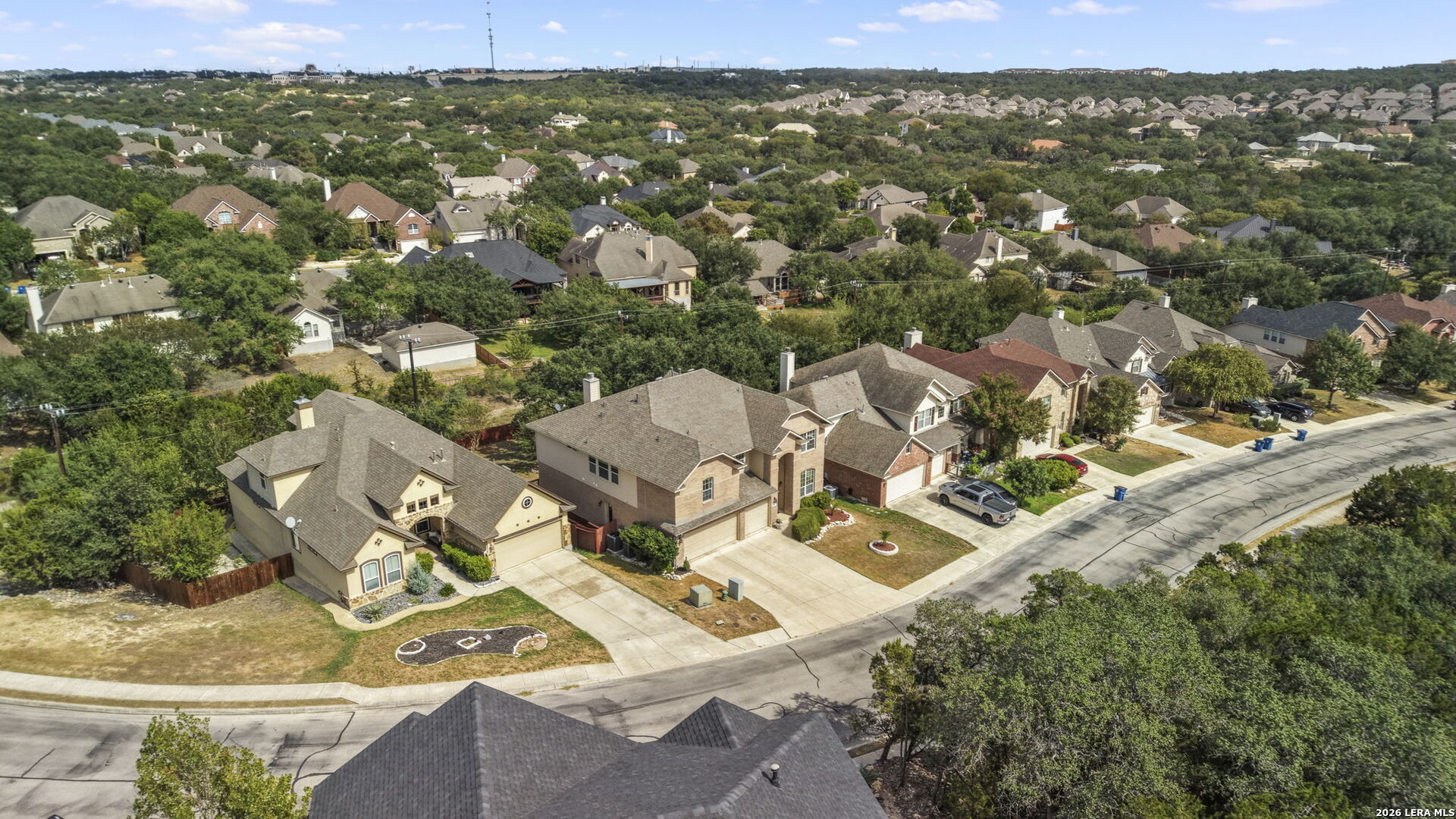 Aerial view of a residential neighborhood with detached homes, tree cover, and curving streets.