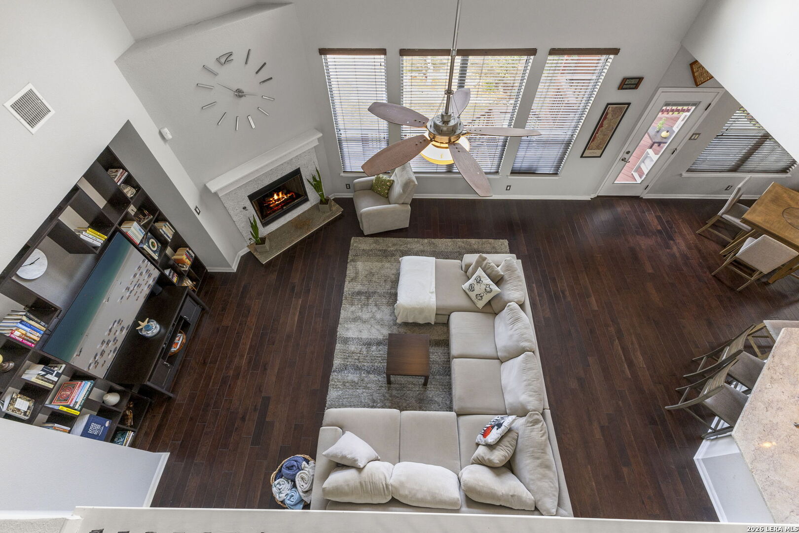 Furnished living room with a light sectional, fireplace, built-in shelves, and dark wood floors, viewed from above.