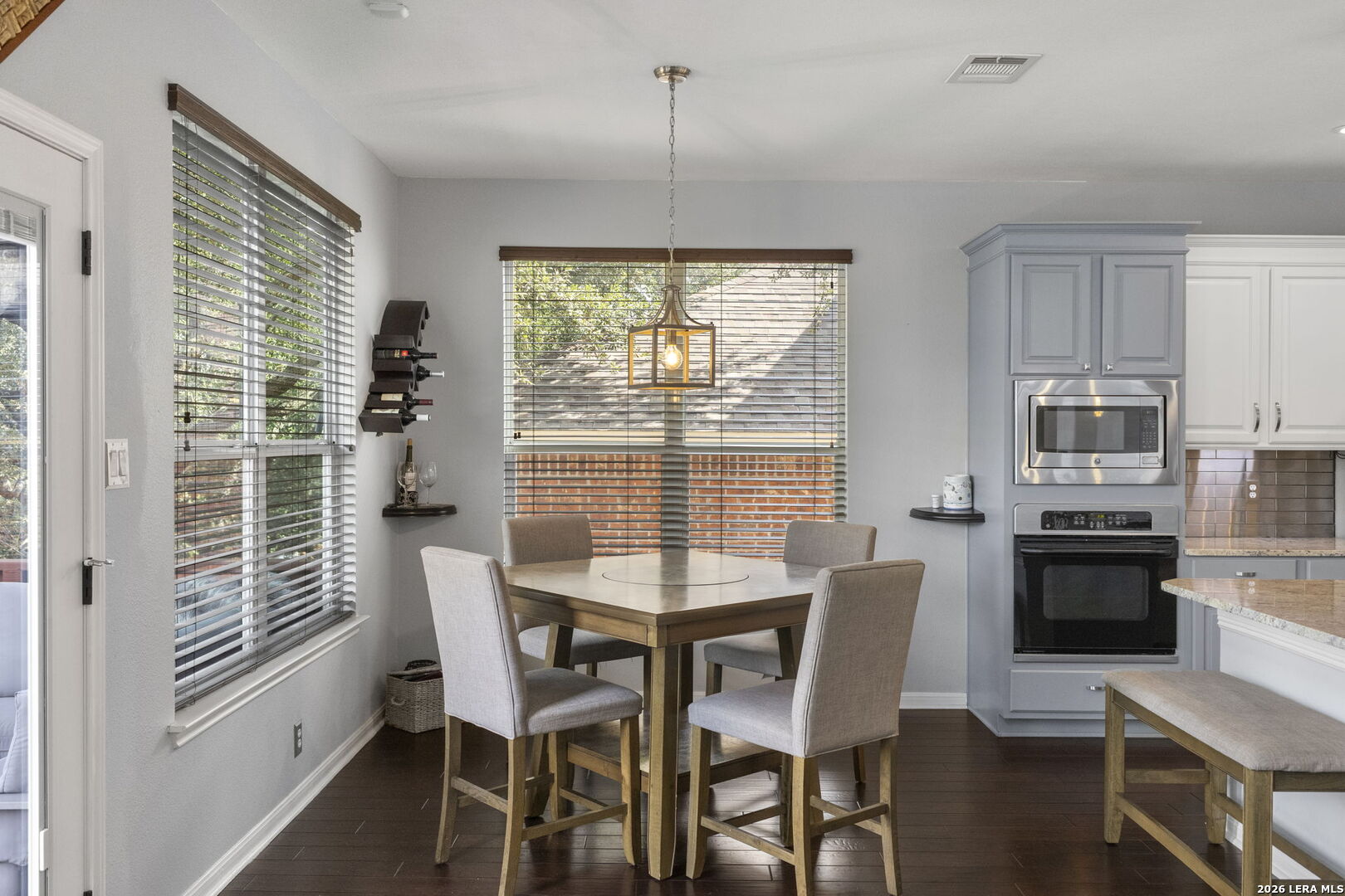 Kitchen dining area with a square table, gray cabinetry, and built-in stainless steel appliances.