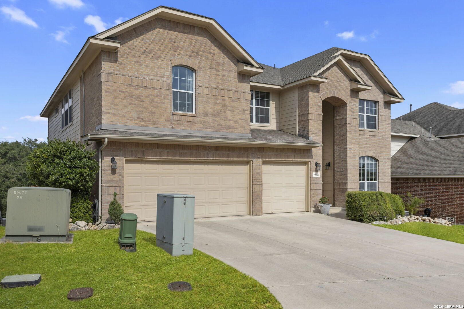 Two-story brick house with a recessed arched entry and three-car garage.