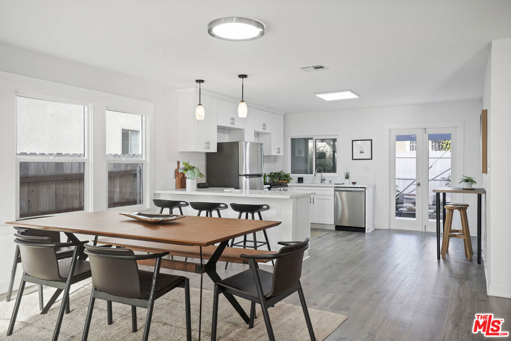 Open-plan kitchen and dining area with a quartz island, stainless appliances, and a large wood dining table.