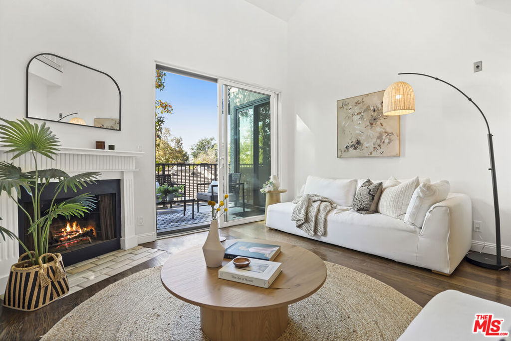 Living room with a white sofa, fireplace, round coffee table, and sliding doors to a balcony.