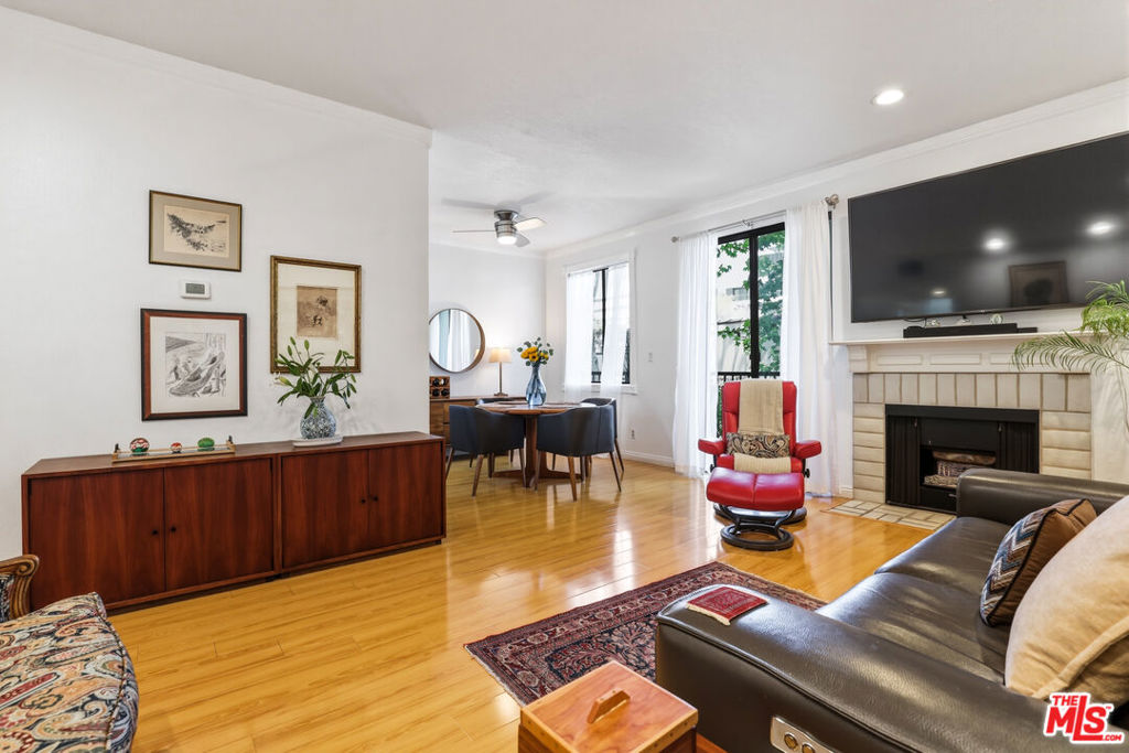 Living room with hardwood floors, a fireplace and mounted television, and a distinctive red lounge chair.