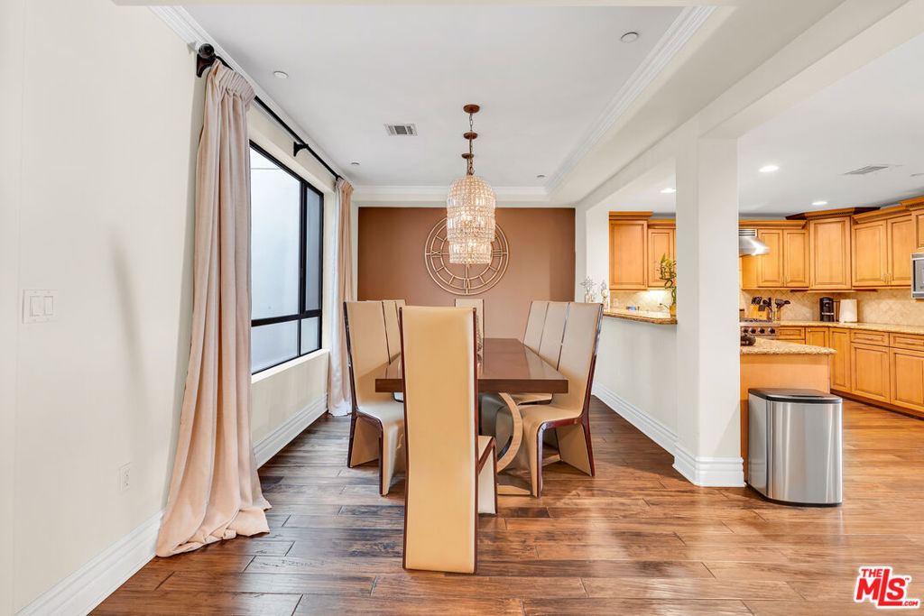 Dining room with a crystal chandelier, tall chairs, and an adjoining wood-cabinet kitchen.