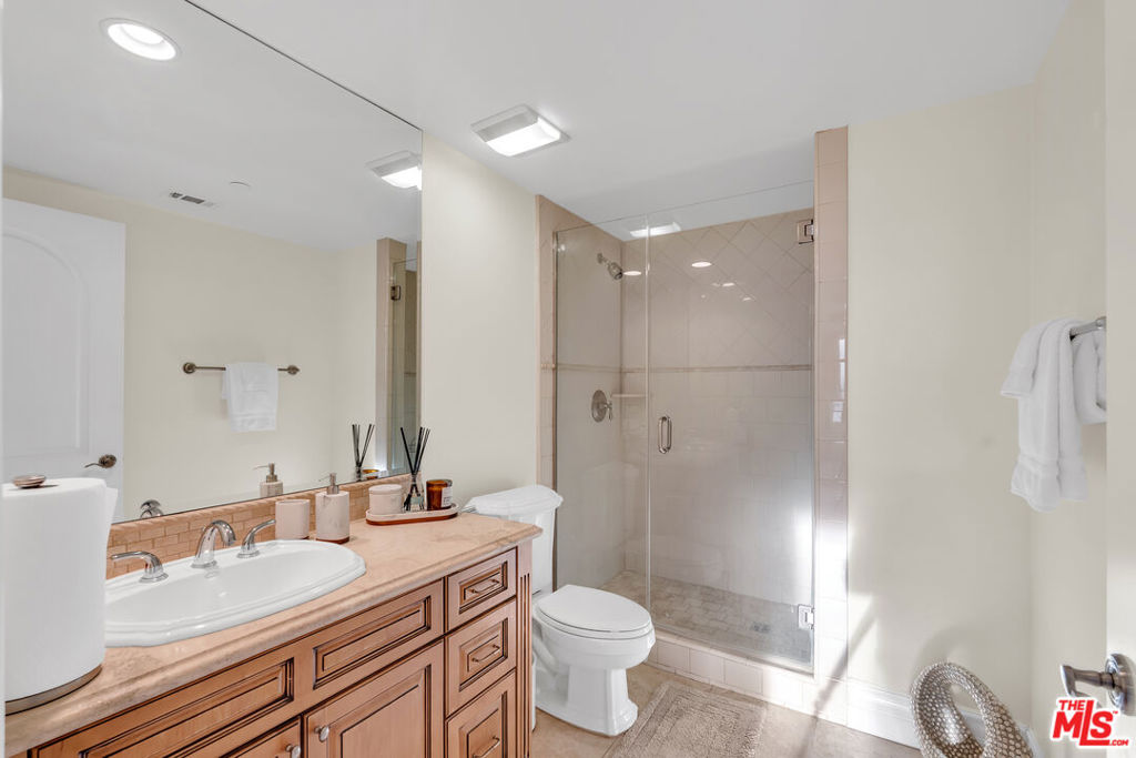 Bathroom with a peach-toned vanity, large mirror, and glass-enclosed shower.
