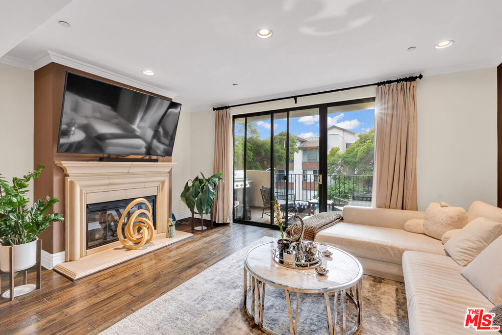Living room with a fireplace, cream sectional sofa, and sliding glass doors to a balcony.