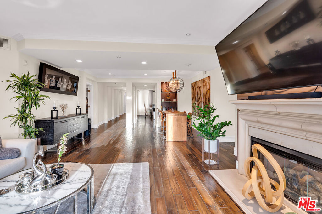 Furnished living room with dark hardwood floors, marble fireplace, and an open dining area.